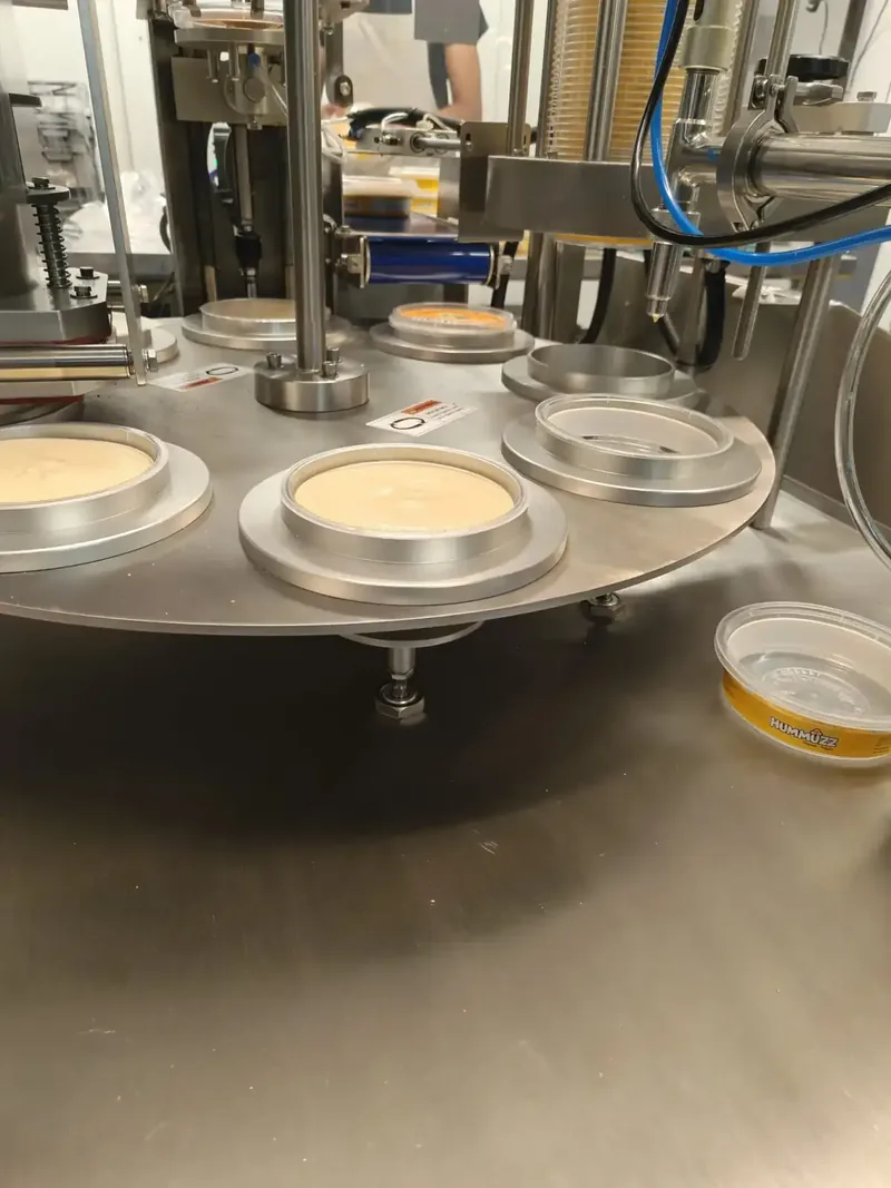 Close-up of hummus cups being filled on the SDH-R rotary carousel with sealed product output