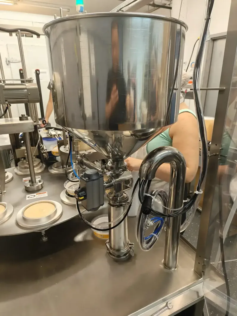 Stainless steel product hopper and piping system feeding hummus into the rotary filler
